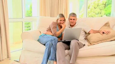 Couple on sofa enjoying a programme on their laptop Stock Footage 2872619