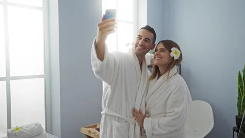 Couple in spa robes taking a selfie indoors, embodying love and relaxation .. Vídeo Stock 303401867