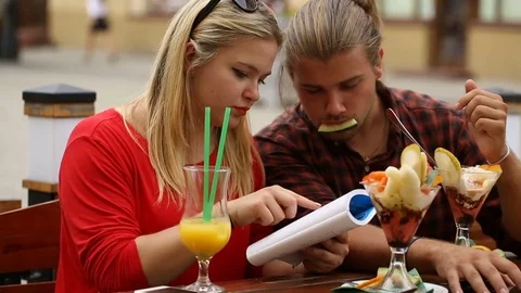 Couple spending time in the restaurant and reading book Stock Footage 77485089
