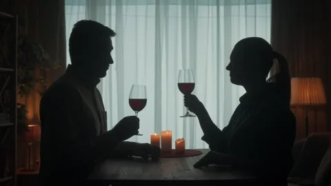 A couple spends an evening with red wine by candlelight, they say a toast, they Stock Footage 245475371