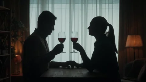 The couple spends the evening with red wine by candlelight. Dark silhouettes of Video stock 245475931