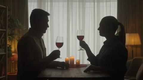 A couple spends an evening with red wine by candlelight, they say a toast, they Stock Footage 245500857
