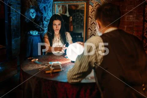 Couple on spiritual seance, witch on background Stock Photos