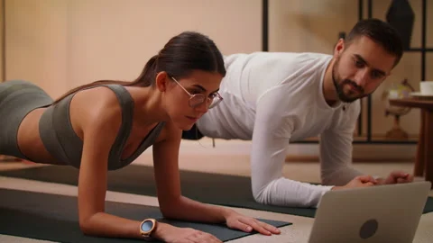 Couple In Sportswear Doing Sports At Home On Mat Watch Fitness Video On Laptop Stock Footage