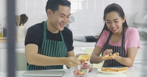 Couple spread strawberry jam on bread together. 스톡 동영상 104073471