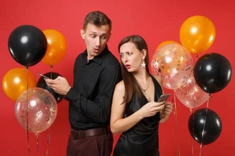 Couple stand back to back messaging in cellphone celebrating birthday holiday Stock Photos
