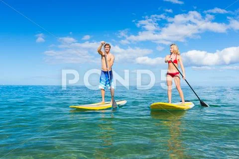 Couple stand up paddle surfing in hawaii Stock Photos