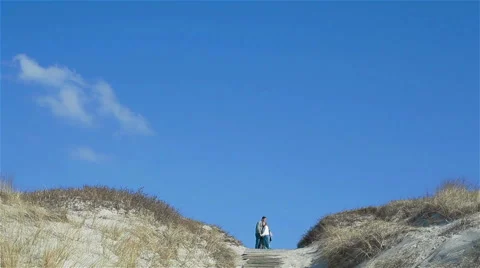 Couple standing and talking on the top of sandy dune hill under beautiful clean Stock Footage 49899499