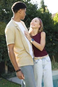 Couple standing at backyard pool, man wearing beige shirt and wristbands, woman Foto stock