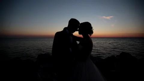 Couple standing on the beach at sunset Stock Footage 70587541