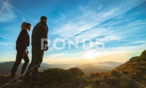 The couple standing on the beautiful mountain sunset background Stock Photos
