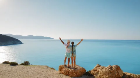 Couple standing on a cliff edge enjoying panoramic sea view in summer Cephalonia Video stock 341451214