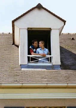 Couple standing at dormer window Fotos Stock