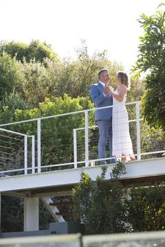 Couple standing on elevated metal cable deck amid shrubs, wearing blue suit and Stock Photos