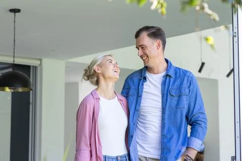 Couple standing facing each other in home doorway, woman looking up, pendant Stock Photos