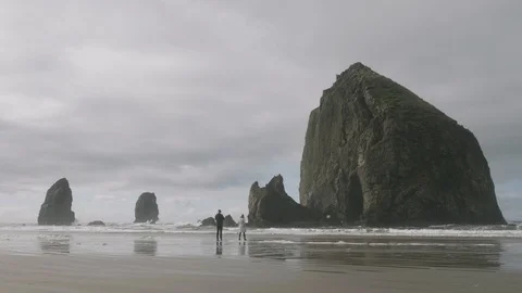 Couple standing in front of huge haystack rock at cannon beach oregon Vídeo Stock 122806748