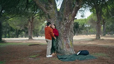 Couple standing leaning tree hugging. Cute pair talking cuddling on nature park. Fotos Stock
