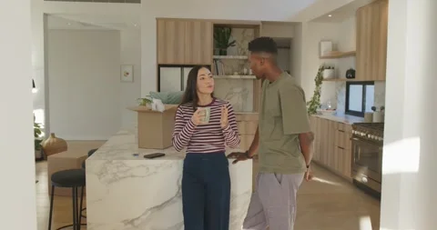 Couple standing at marble kitchen island unpacking boxes, woman sipping mug Stock Footage 337236603
