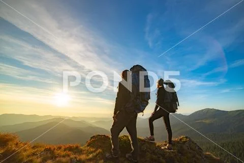 The couple standing on the mountain with a picturesque sunset background Stock Photos