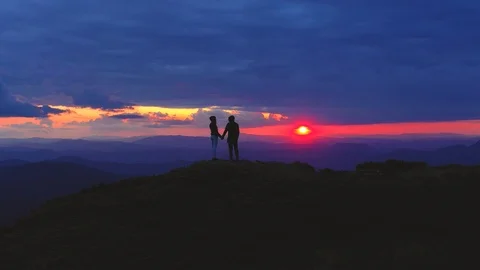 The couple standing on the mountain on a sunset background Vídeos de archivo 113753124