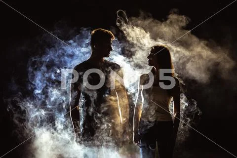The couple standing near the smoke in the dark Stock Photos