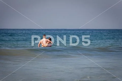 Couple standing in ocean Stock Photos