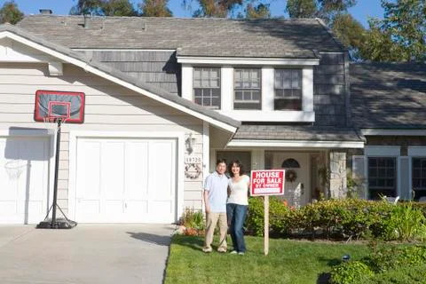 Couple Standing Outside House With Real Estate Sign Stock Photos