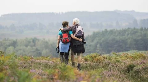 A couple standing on a path looking at the view over wooded hills Fotos Stock