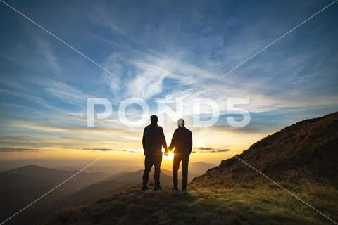 The couple standing on the rock with a picturesque sunrise Stock Photos