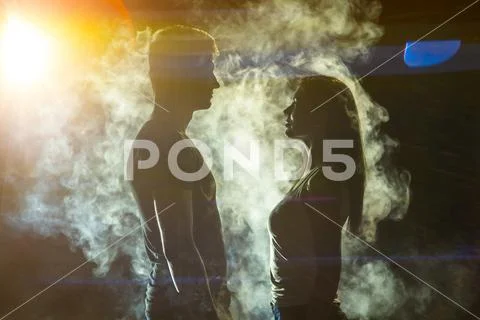The couple standing in the smoke on a bright light background Stock Photos