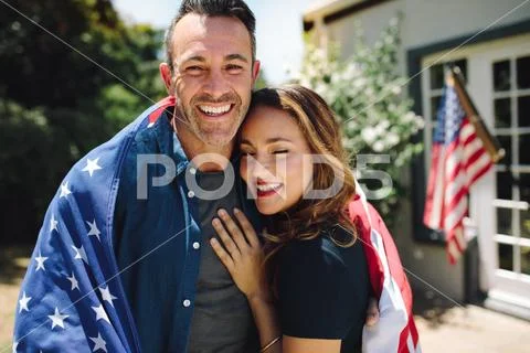 Couple standing together carrying the american flag Stock Photos