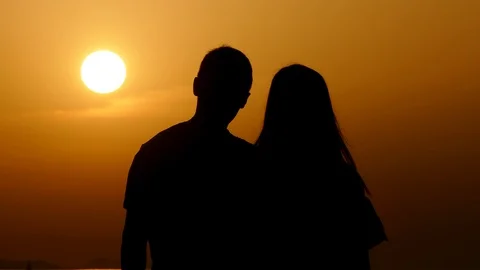 Couple standing together looking at red sun in last moments of sunset in Zadar Stock Footage 90265471
