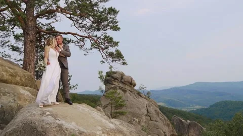Couple standing on top of mountain. Strong wind and sunset. Stock Footage 234086686
