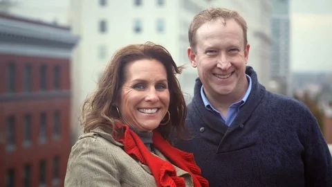A couple stands and smiles for the camera in the city on a fall day Stock Footage 98382567