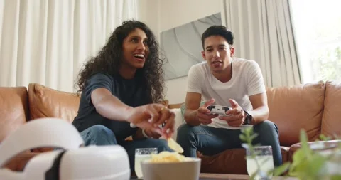 Couple starting console game, playing with white controllers on couch, sharing Stock Footage 341468117