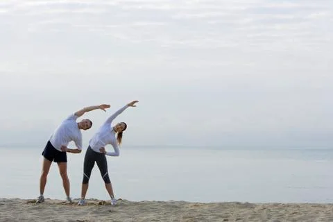Couple stretching on beach Stock Photos