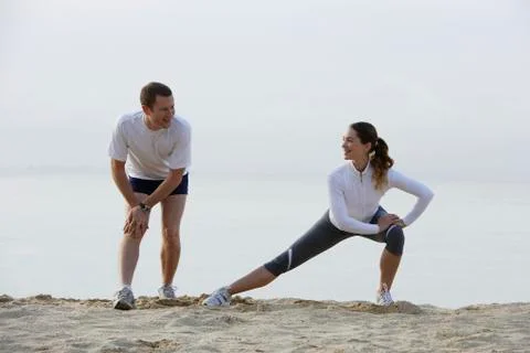 Couple stretching on beach Stock Photos