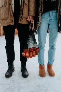 Couple strolling at the christmas market with string bag with mandarin. man a Stock Photos