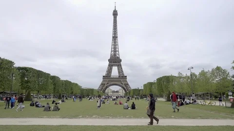 Couple strolling past Eiffel Tower people sitting on grass picnic Paris France Stock Footage 93999061