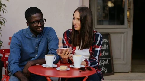 Couple of students sitting in cafe and talking. Cute young woman holding Stock Footage 81833843