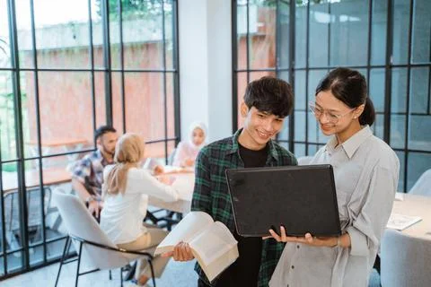 A couple of students using a laptop standing Stock Photos