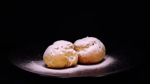 Couple of sugar powdered eclairs, rotating on black background to the right Stock Footage 74885132