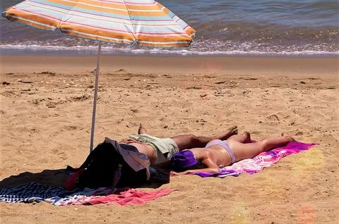 Couple sunbathing on the beach Stock Photos