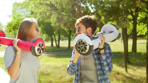 Couple in sunglasses walking with hover boards in hands Stock Footage 74691108
