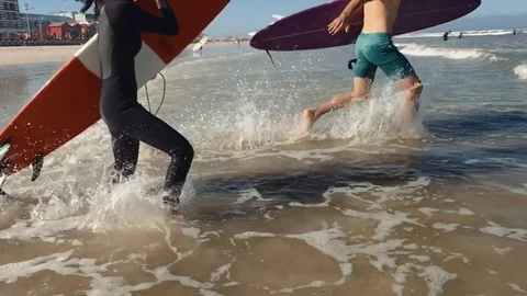 Couple with surfboards running into waves Video stock 76521675