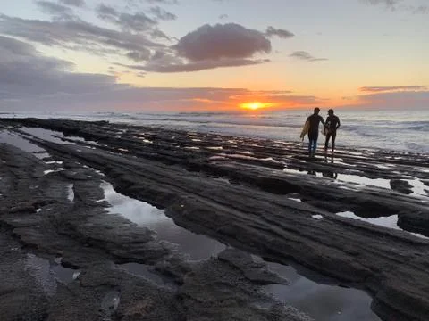 Couple of surfers are going to conquer the waves at sunset on the most popular  Stock Photos