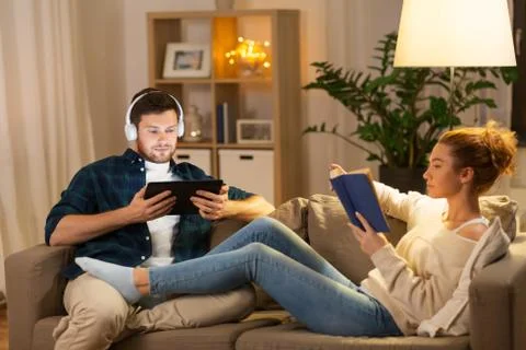 Couple with tablet computer and book at home Stock Photos