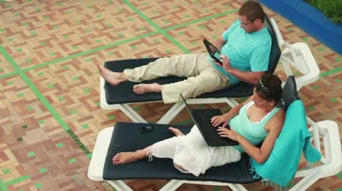 Couple with tablet computer and laptop relaxing on sunbeds Vidéo 10842116