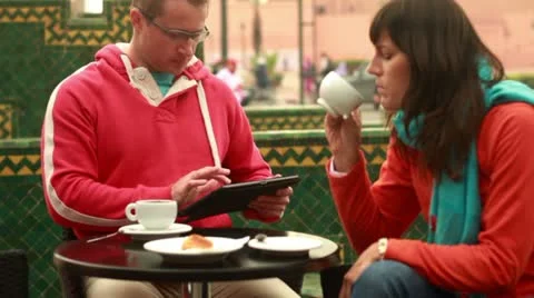 Couple with tablet computer in cafe by city street, steadicam shot Stockbeeldmateriaal 10842241