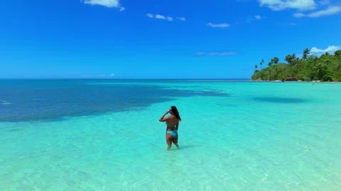 A couple takes a refreshing dip in the crystal-clear waters bordering a white Stock Footage 339976260